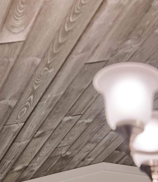 wooden paneling on slanted ceiling with small lighting fixture